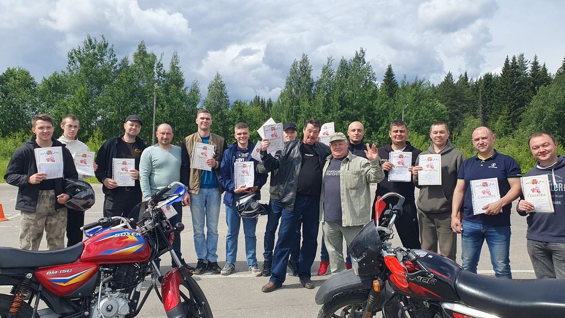 Группа выпускников автошколы с грамотами на автодроме