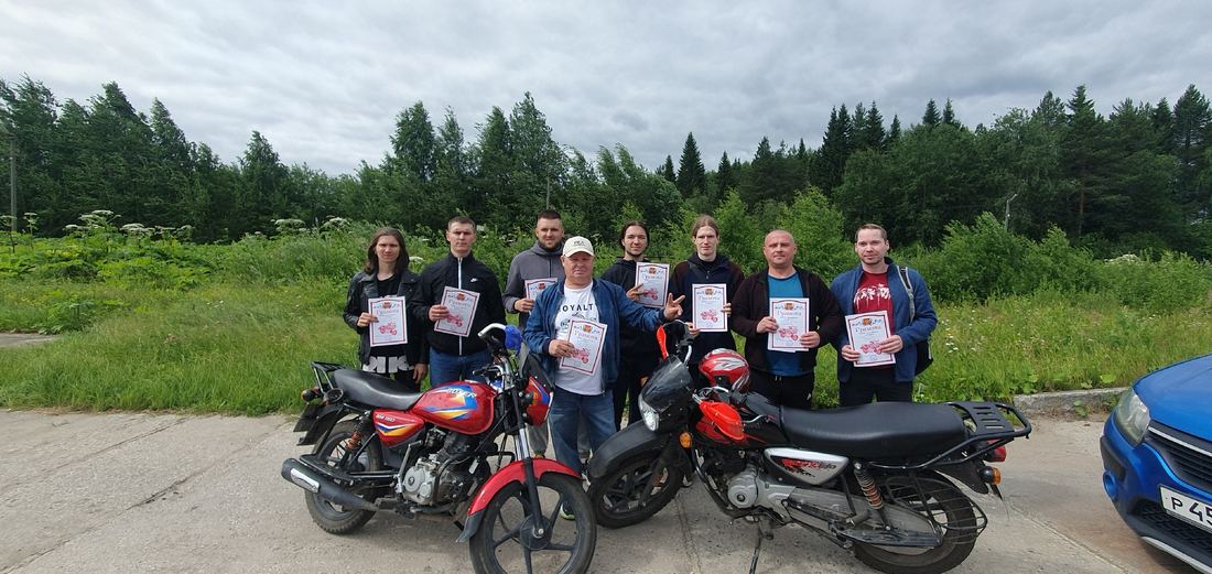 Группа выпускников автошколы с грамотами у мотоциклов