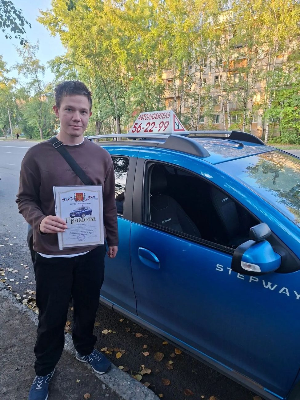 Выпускник со свидетельством у синего учебного Renault Sandero Stepway